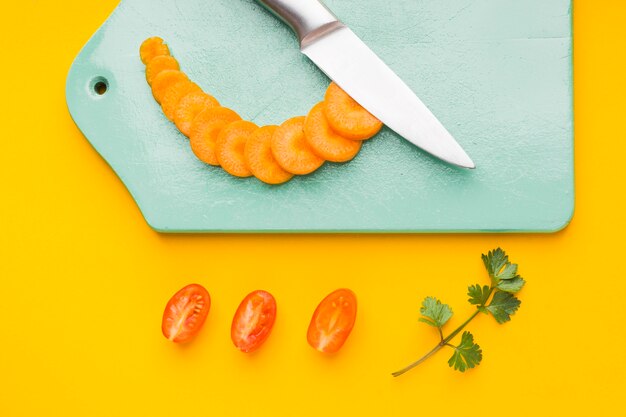 Top view sliced carrot on cutting board with tomatoes