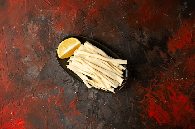 Foto gratuita formaggio a fette vista dall'alto con pezzo di limone all'interno del piatto su sfondo scuro