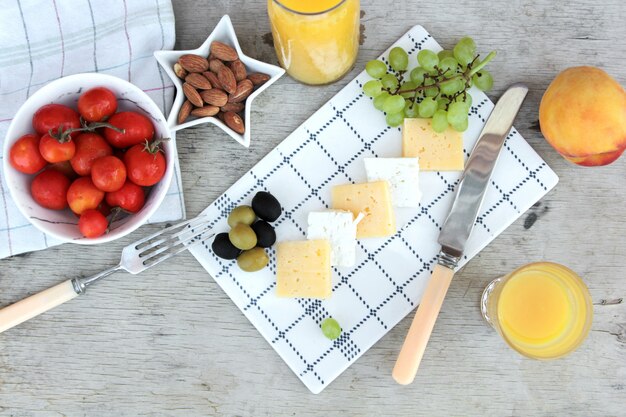 Top view sliced cheese with olives grapes tomatoes and orange juice