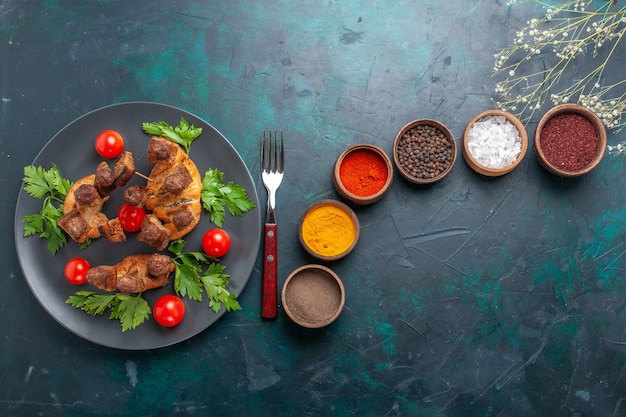 Vista dall'alto affettato di carne cotta con pomodorini e diversi condimenti su sfondo blu