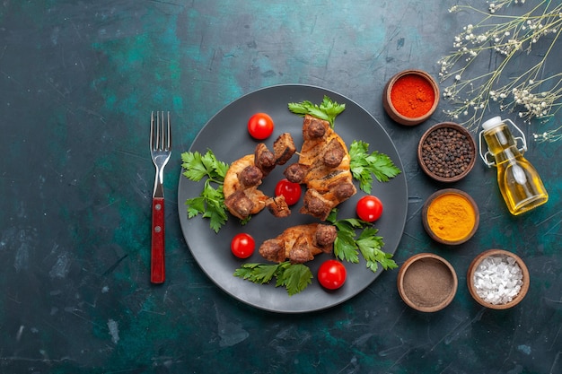 Top view sliced cooked meat with cherry tomatoes inside plate and with seasonings on blue background