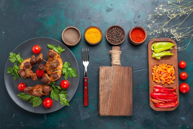 Top view sliced cooked meat with cherry tomatoes inside plate and with seasonings on blue background