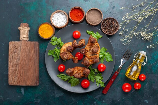 Top view sliced cooked meat with greens cherry tomatoes oil and seasonings on blue background