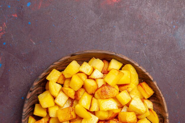 Top view sliced cooked potatoes inside brown plate on the dark desk