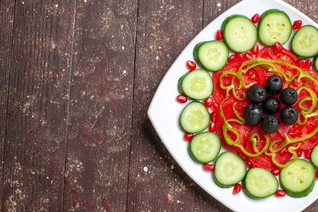 Top view sliced cucumbers with olives inside plate on a brown rustic desk diet salad vegetables vitamine health