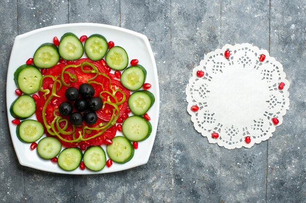 灰色の素朴なデスクサラダ野菜ビタミン健康ダイエットのプレートの内側にオリーブとスライスしたキュウリの上面図