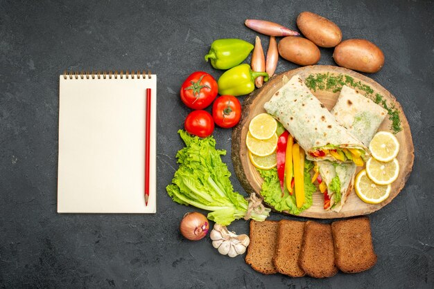 Top view of sliced delicious shaurma meat sandwich with bread and vegetables on black