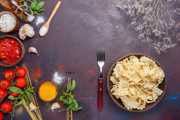 Top view sliced dough with tomato sauce and tomatoes on dark desk meal dough food pasta dinner