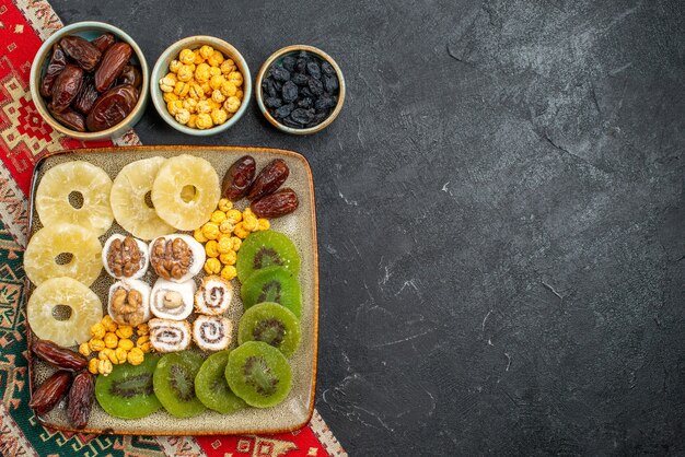 Top view sliced dried fruits pineapple rings and kiwis on grey background dry fruits raisin sweet vitamine sour health