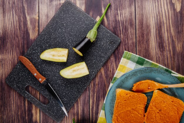 Top view of sliced eggplant and kitchen knife on board for cooking and toasts with eggplant caviar