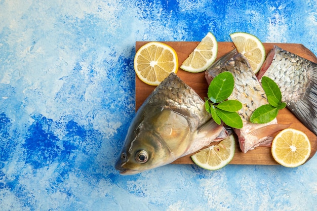 상위 뷰는 파란색 표면에 레몬 조각과 신선한 생선을 슬라이스
