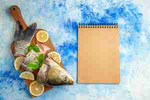 Foto gratuita vista dall'alto affettato pesce fresco con fette di limone sulla superficie blu