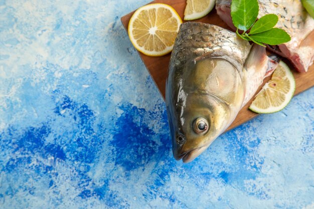 Вид сверху нарезанной свежей рыбы с ломтиками лимона на голубой поверхности
