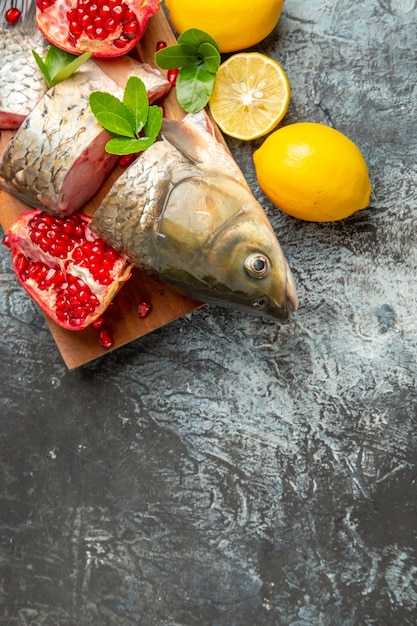Вид сверху нарезанной свежей рыбы с гранатами и лимоном на светлой поверхности