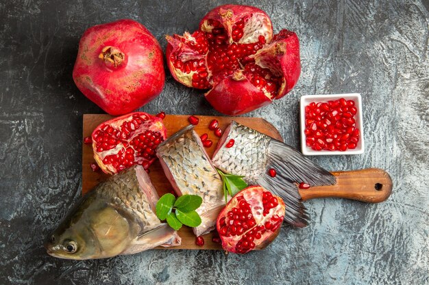 Top view sliced fresh fish with pomegranates on light-dark surface