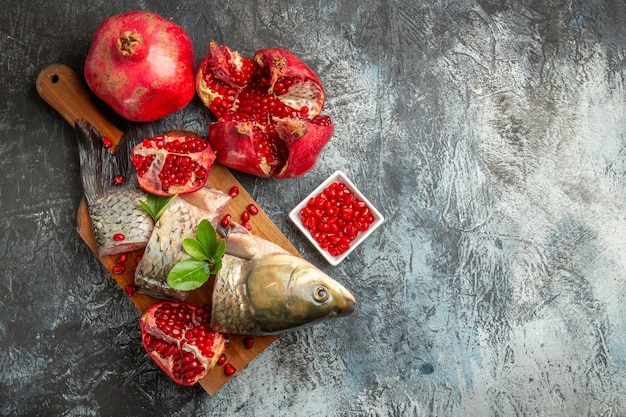 Top view sliced fresh fish with pomegranates on light-dark surface