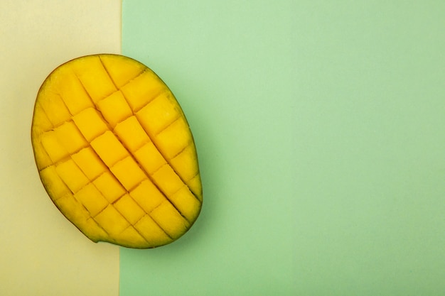 Top view of sliced fresh mango on yellow and green surface