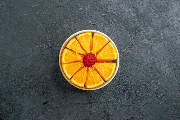 暗い表面の柑橘類のエキゾチックなフルーツのプレート内のスライスされた新鮮なオレンジの上面図