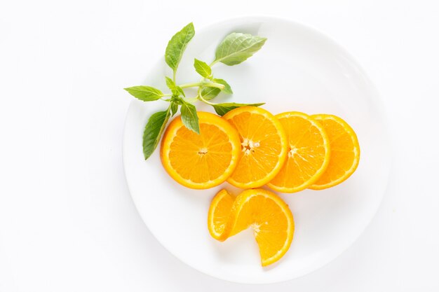 白い背景のエキゾチックなフルーツジュースの白いプレート内の新鮮なオレンジをスライスしたトップビュー