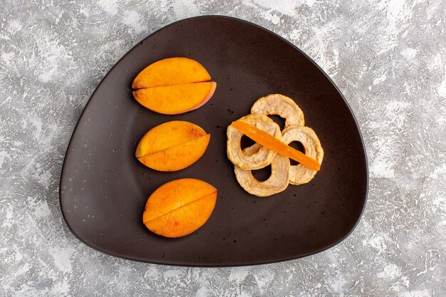 Top view of sliced fresh peaches inside plate with pineapple rings on light white surface