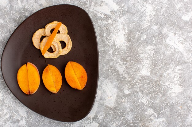 Top view of sliced fresh peaches inside plate with pineapple rings on the light white surface