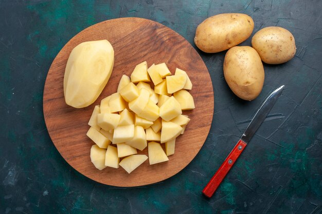 Вид сверху нарезанный свежий картофель и овощи на темно-синем фоне
