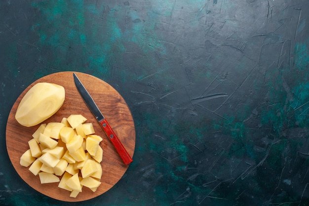Бесплатное фото Вид сверху нарезанный свежий картофель и овощи с ножом на темно-синем фоне