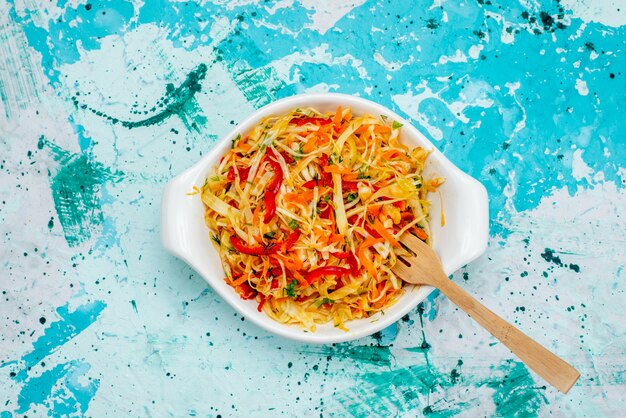 Top view sliced fresh salad vegetable salad inside plate with spoon on the bright-blue background food meal vegetable salad snack