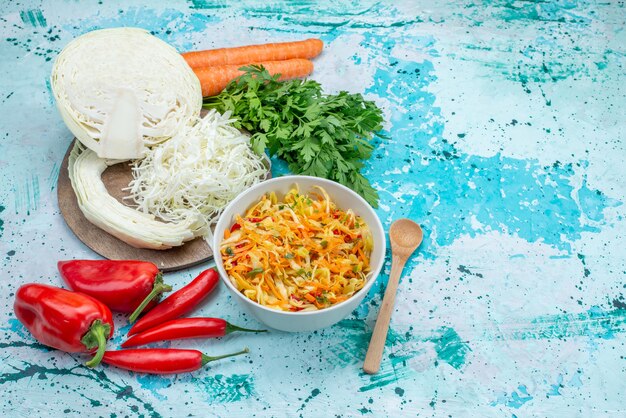 Top view sliced fresh vegetables long and thin pieced salad inside plate with greens cabbage peppers on the bright-blue background food meal vegetable salad snack