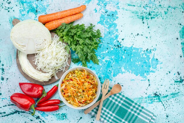 Top view sliced fresh vegetables long and thin pieced salad inside plate with greens cabbage peppers on the bright-blue background food meal vegetable salad