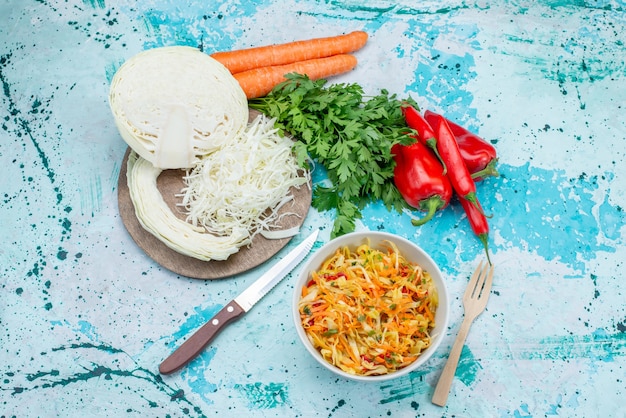 Top view sliced fresh vegetables long and thin pieced salad inside plate with greens cabbage peppers on the bright-blue  surface food meal vegetable lunch healthy salad