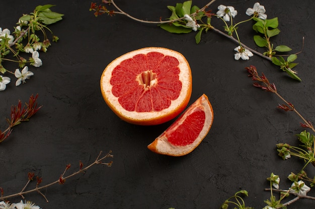 top view sliced grapefruit mellow juicy ripe isolated along with white flowers on the dark background