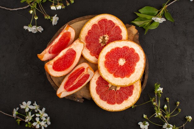 top view sliced grapefruits fresh mellow juicy on the brown desk and dark background