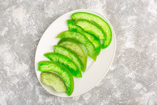 Top view sliced green cucumbers inside plate on white surface