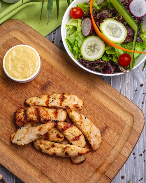 Free photo top view sliced grilled chicken breast with sauce and vegetable salad