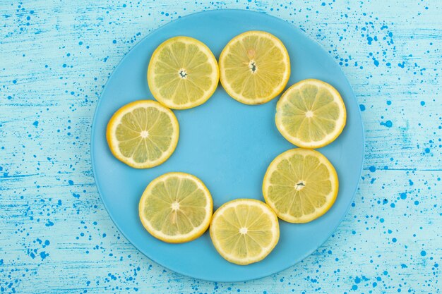 상위 뷰는 밝은 파란색 바닥에 파란색 접시 안에 레몬 신 달콤한 육즙 부드러운 슬라이스