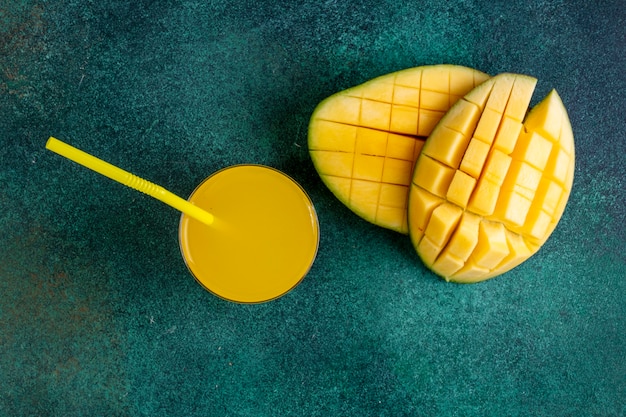 Top view sliced mango with a glass of orange juice on green