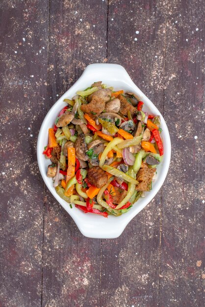 Top view sliced meat dish with cooked vegetables inside plate on the brown wooden table food meal vegetable meat