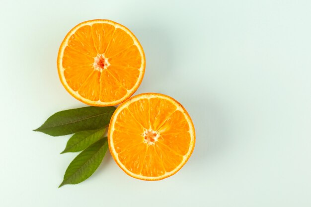 A top view sliced orange fresh ripe juicy mellow isolated half cut pieces with green leaves on the white background fruit color citrus
