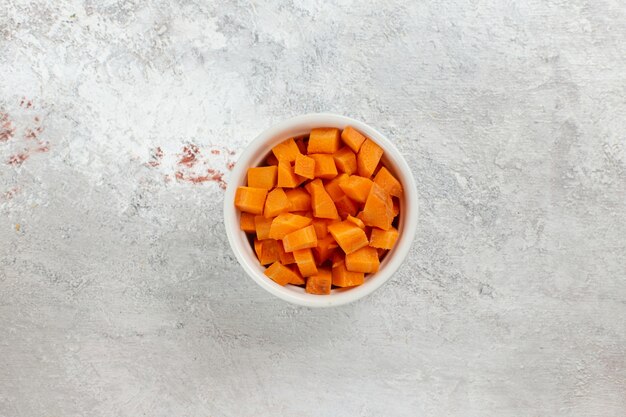 Top view sliced orange vegetable inside little pot on white background