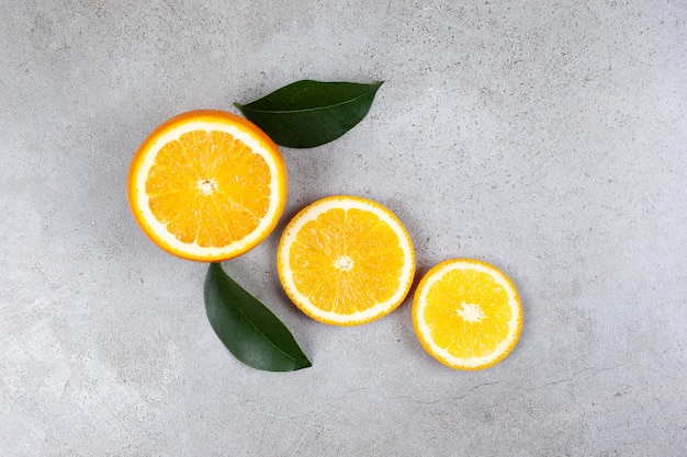 Top view of sliced orange with leaves on grey table.