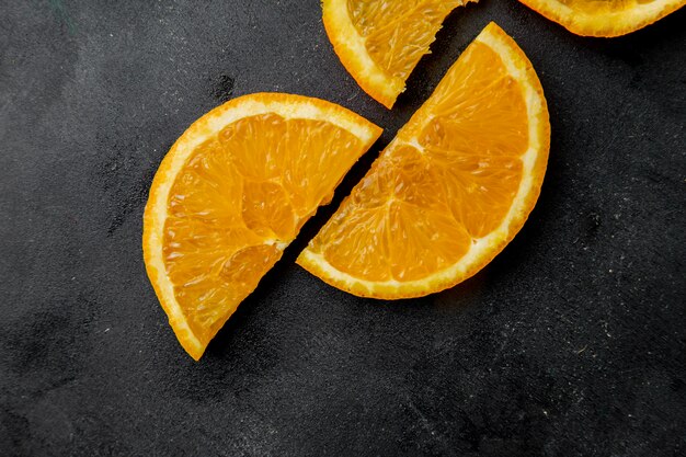 Top view of sliced oranges on black surface