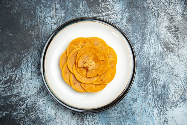 Top view of sliced persimmon designed inside plate on light surface