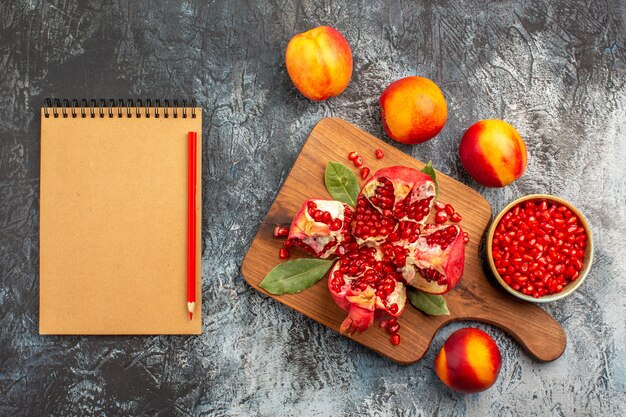 Top view of sliced pomegranates with peaches on dark floor