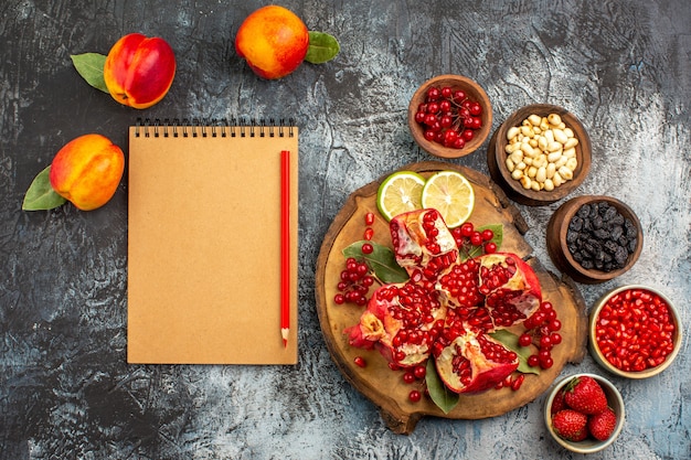 Top view of sliced pomegranates with peaches on light-dark floor