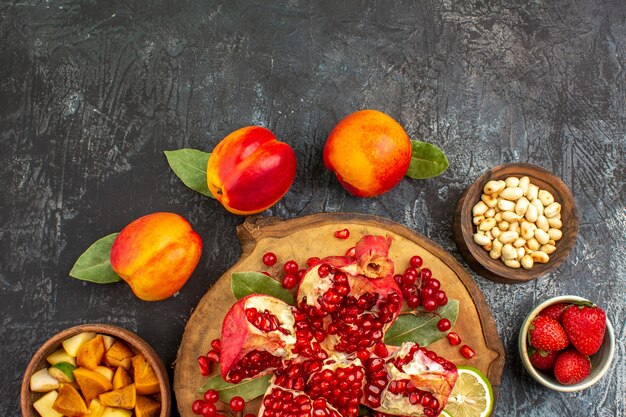 Top view of sliced pomegranates with peaches on light-dark table