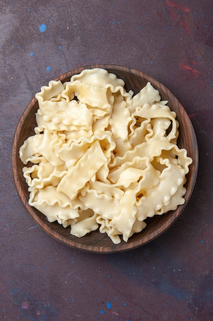 Top view sliced raw dough inside brown plate on dark background meal dough food pasta dinner