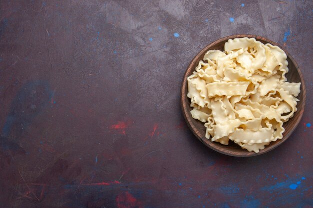 濃い紫色の背景の茶色のプレート内のスライスされた生の生地の上面図食事生地食品パスタディナー