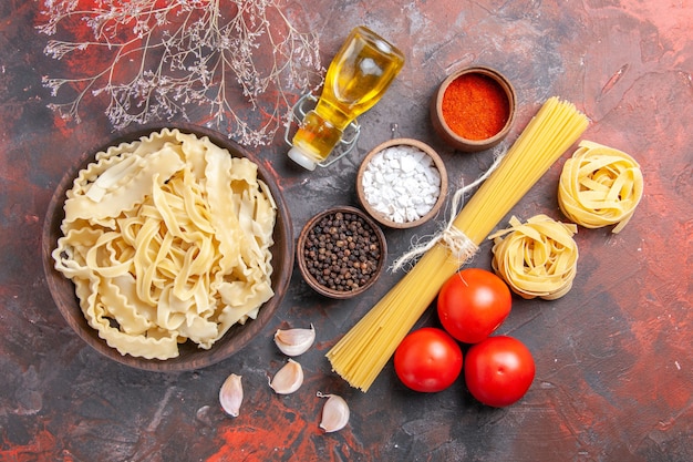 Foto gratuita vista dall'alto a fette di pasta cruda con condimenti su pasta di superficie scura cibo pasta scura