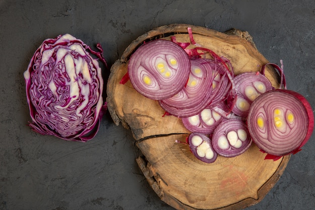 Top view of sliced red cabbage and red onion on a wooden cutting board on black